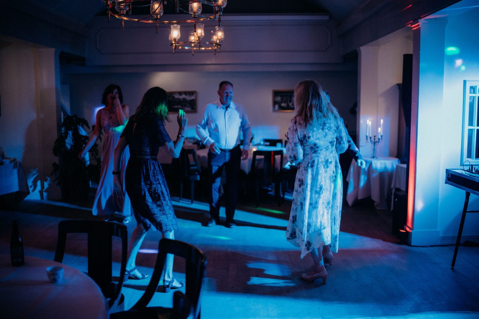 A lively indoor party scene with friends dancing under blue lighting, enjoying nightlife vibes.